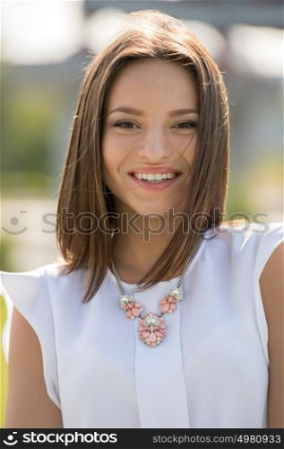 Beautiful young woman wearing elegant dress walking in summer park