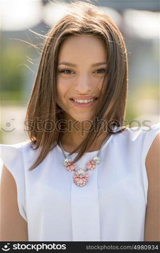 Beautiful young woman wearing elegant dress walking in summer park