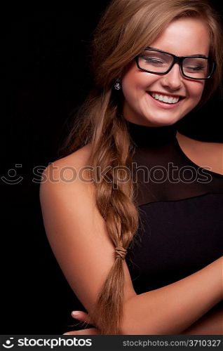 Beautiful young woman wearing glasses, smiling on black background