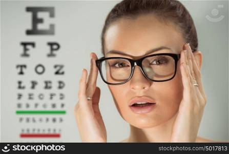 Beautiful young woman wearing glasses standing in front of eye test