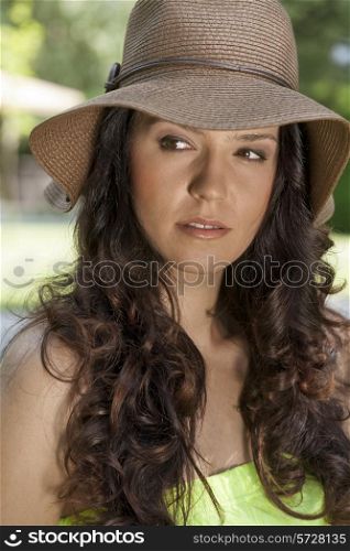 Beautiful young woman wearing sunhat looking away in park