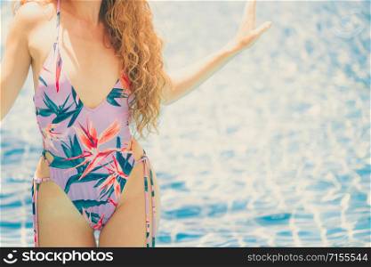 Beautiful young woman wearing swimsuit is on summer vacation. Travel and lifestyle.. Happy young woman in swimsuit at swimming pool.