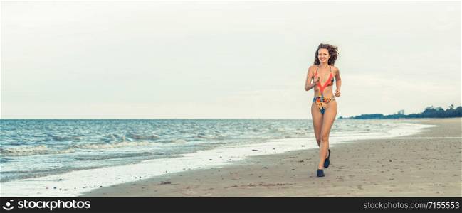 Beautiful young woman wearing swimsuit is on summer vacation. Travel and lifestyle.. Attractive woman runs on sand beach in summer.