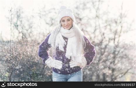 Beautiful young woman wearing warm clothing in snowflakes and winter day outdoors. Half length of cute girl wearing wool cap, scarf and purple sweater. Female person in cold weather.