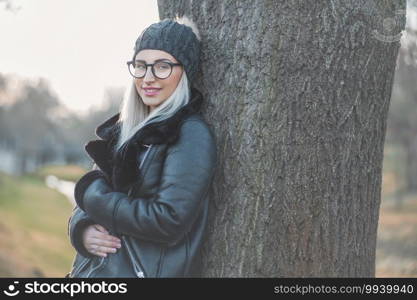 Beautiful young woman wearing warm clothing, winter day outdoors. Half length of cute girl wearing wool cap and black jacket. Copy space for text.