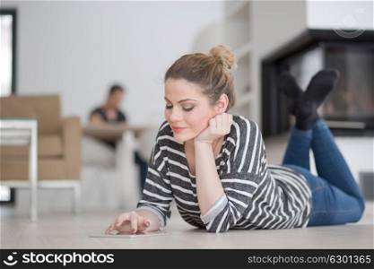 beautiful young woman websurfing using tablet computer on the floor in front of fireplace on cold winter day at home
