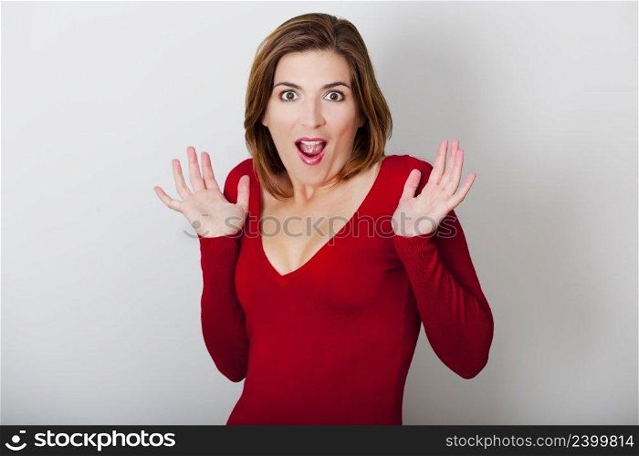 Beautiful young woman with a astonished expression, against a gray wall
