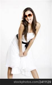 Beautiful young woman with a white dress and sunglasses showing her tongue out