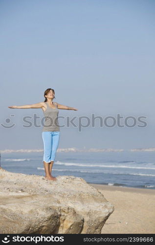 Beautiful young woman with arms open, relaxing on the beach