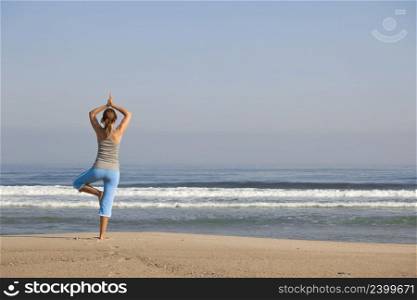 Beautiful young woman with arms open, relaxing on the beach