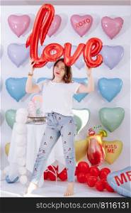 beautiful young woman with balloon in the form of a love in hands on many colorful heart balloons background. smiles,funny Valentine s Day birthday party. beautiful young woman with balloon in the form of a love in hands on many colorful heart balloons background. smiles,funny Valentine s Day birthday party.