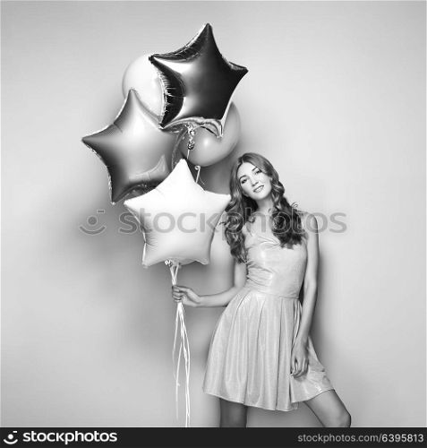 Beautiful Young Woman with Balloons on a White Background. Birthday and Party. Girl in Gray Dress at the festival. Black and White photo