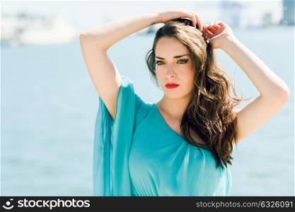 Beautiful young woman with blue eyes wearing blue dress in the beach.