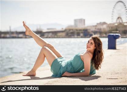 Beautiful young woman with blue eyes wearing blue dress in the beach. Happy girl with beautiful legs