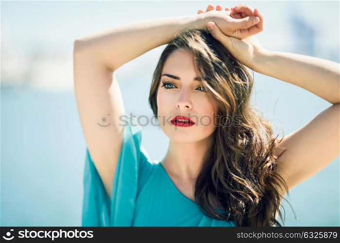 Beautiful young woman with blue eyes wearing dress in the beach.