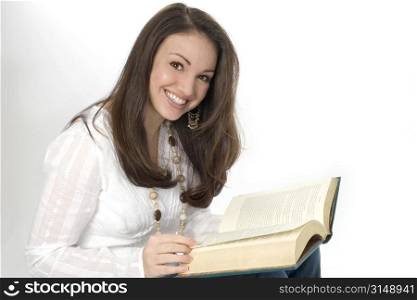 Beautiful young woman with book smiling towards camera. Shot in studio.