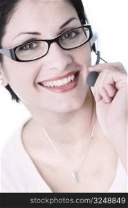 Beautiful young woman with charming big green eyes is bearing modern glasses and receiving calls on a headset.