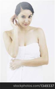 Beautiful young woman with clean skin in white towel against white background. Facial treatment, cosmetology, beauty and wellness spa.