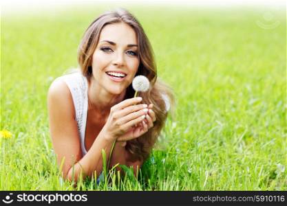 beautiful young woman with dandelion. beautiful young woman with dandelion lying on grass