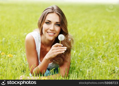 beautiful young woman with dandelion lying on grass. beautiful young woman with dandelion