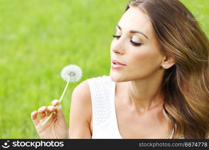 beautiful young woman with dandelion lying on grass. beautiful young woman with dandelion. beautiful young woman with dandelion