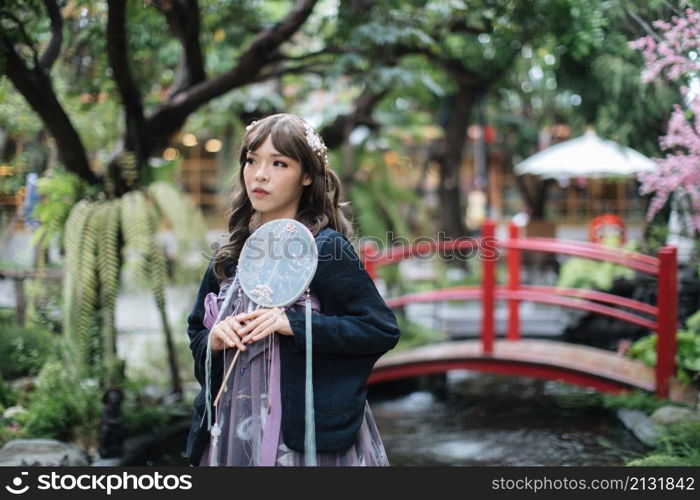 Beautiful young woman with dark blue Chinese lolita dress with Chinese garden