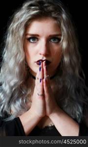 Beautiful young woman with dark make up praying