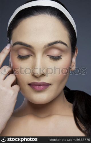 Beautiful young woman with eyes closed over colored background