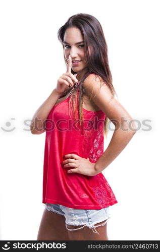 Beautiful young woman with finger in front of mouth, asking to make less noise, isolated over white