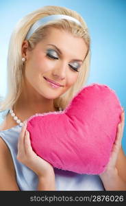 Beautiful young woman with fluffy heart pillow