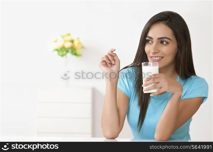 Beautiful young woman with glass of milk at home
