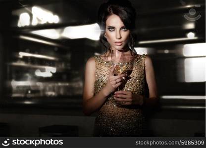 Beautiful young woman with glass of wine standing in interior.