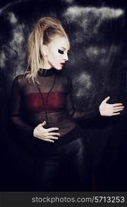 Beautiful young woman with gothic makeup on black background