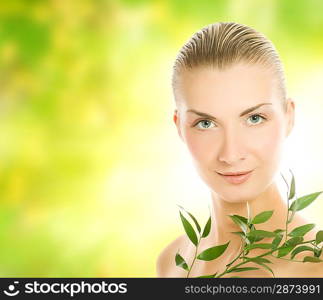 Beautiful young woman with green plant over abstract blurred background
