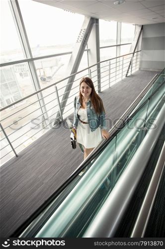 Beautiful young woman with handbag walking at modern airport terminal