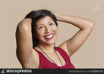 Beautiful young woman with hands in hair over colored background