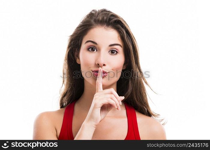 Beautiful young woman with her finger in front of mouth, isolated over a white background