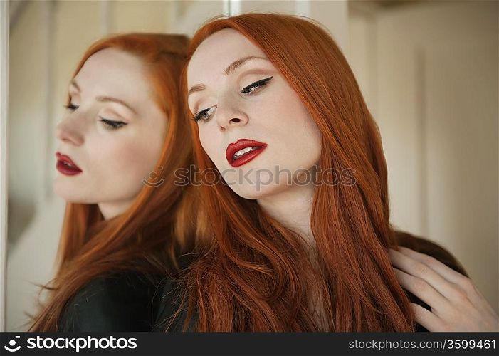 Beautiful young woman with her reflection in mirror