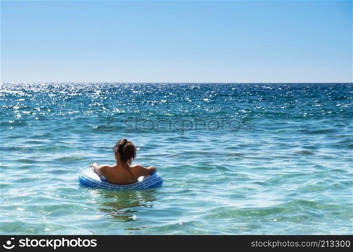 Beautiful young woman with inflatable ring relaxing in the sea.
