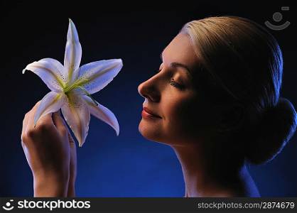 Beautiful young woman with lily flower toned in blue