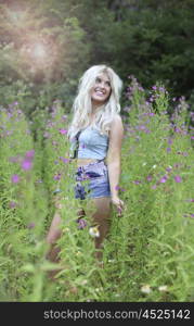 Beautiful young woman with long blonde hair in long grass