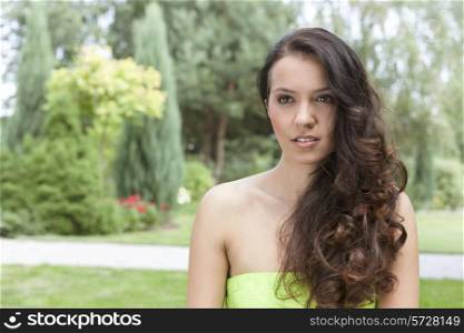 Beautiful young woman with long wavy hair in park