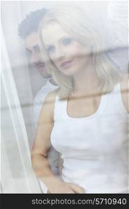 Beautiful young woman with man looking through hotel window