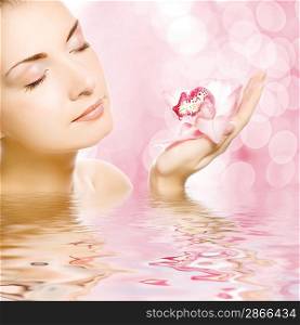 Beautiful young woman with orchid reflected in water