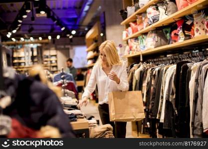 Beautiful young woman with shopping bags standing at the clothing store