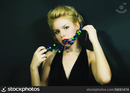 beautiful young woman with stylish hair and beads on black background