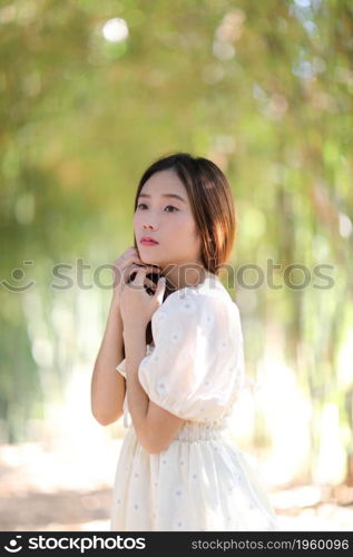 Beautiful young woman with white dress on bamboo forest background