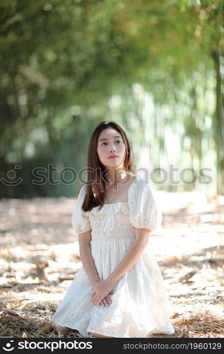 Beautiful young woman with white dress on bamboo forest background