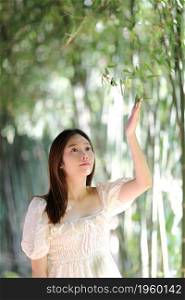 Beautiful young woman with white dress on bamboo forest background