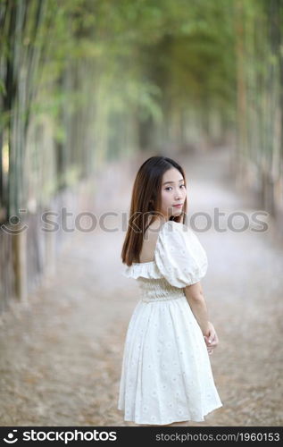 Beautiful young woman with white dress on bamboo forest background